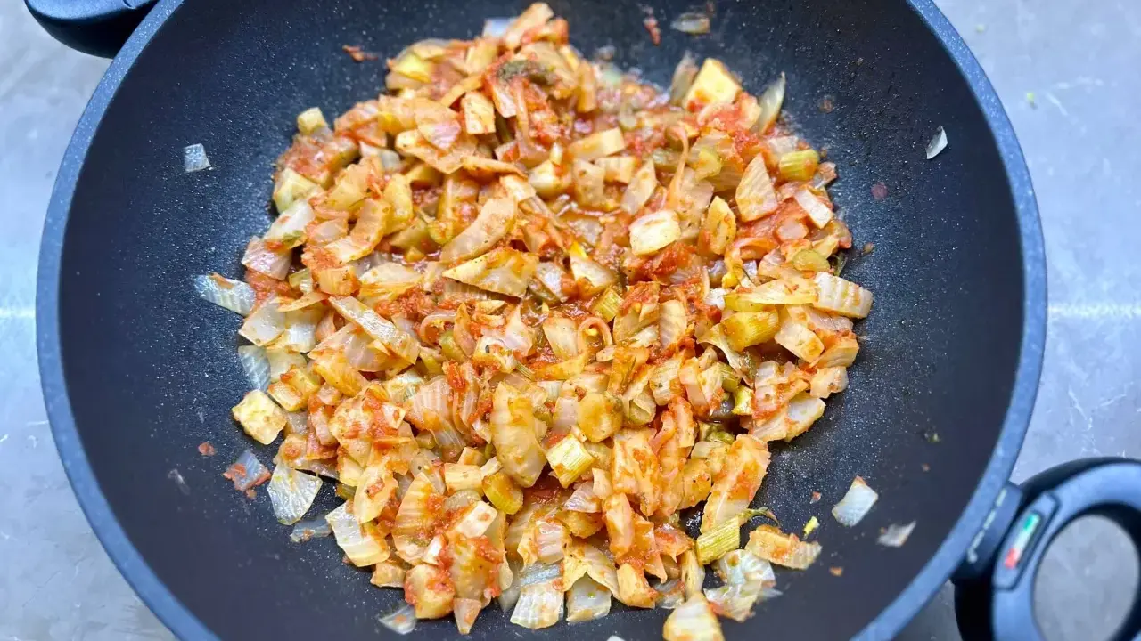 Finocchi in padella, tagliati a pezzi e cotti con pomodoro e spezie, emanano un profumo invitante.