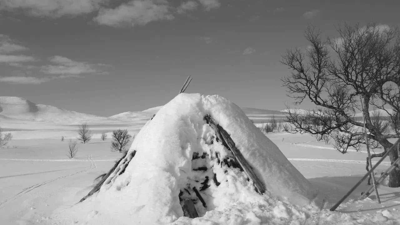 Snötäckt kåta i ett vinterlandskap. Vackra samiska ord som "guovssahas" (norrsken) eller "njárga" (flod) kan beskriva denna tysta, vita värld.