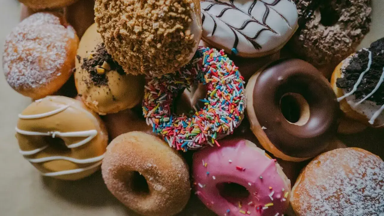 Kolorowe pączki z posypką, lukrem i cukrem pudrem. Zastanawiasz się, ile kalorii ma pączek?