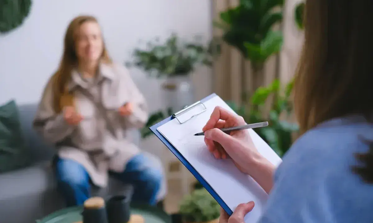 Psycholog notuje podczas sesji. Zastanawiasz się, ile zarabia psycholog policyjny?
