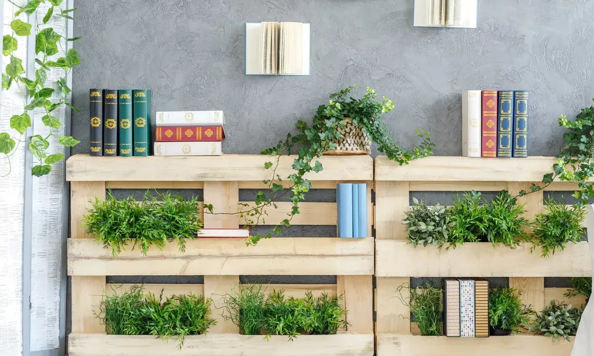 Scaffali in pallet con piante e libri, perfetti per idee per abbellire casa fai da te.