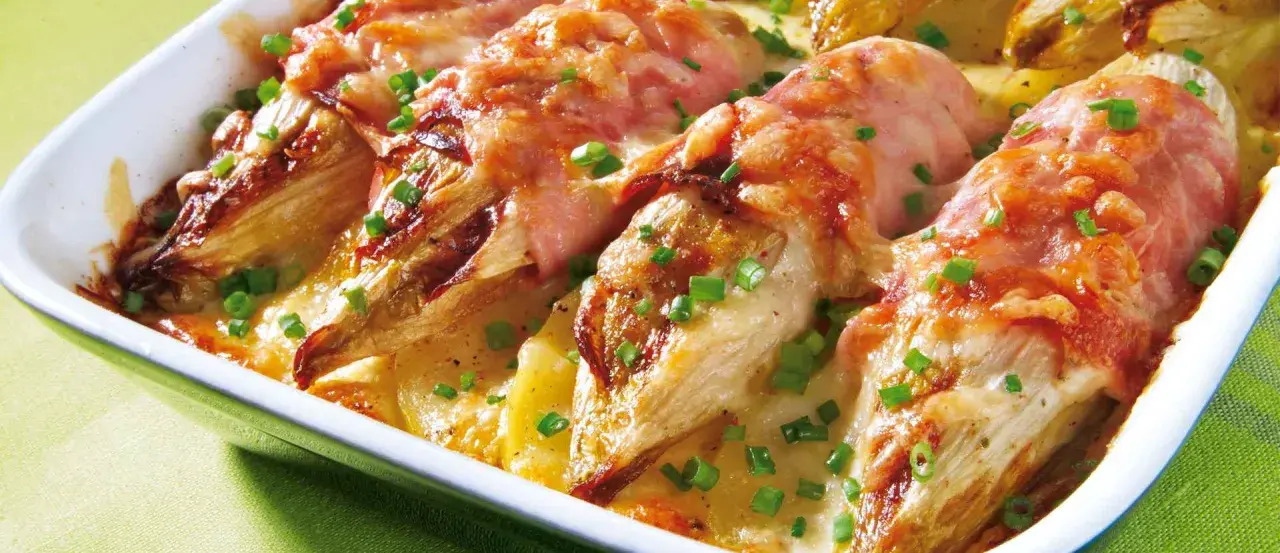 Gebackener Chicorée in Schinken gewickelt, überbacken mit Käse und Kartoffeln. Ein köstliches Gericht für alle, die Rezepte mit Schinken lieben.