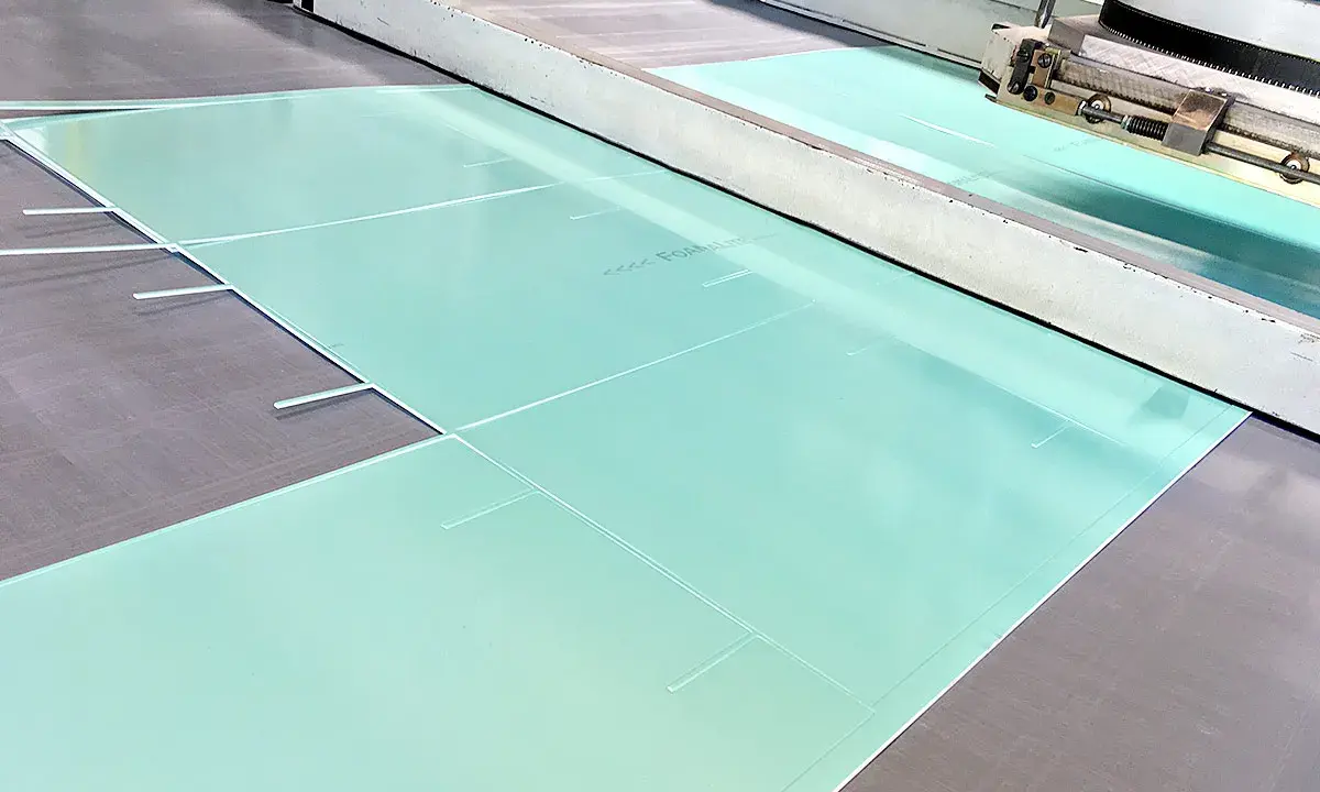 Große, hellgrüne Platten aus PVC-Schaum werden in einer Produktionsanlage zugeschnitten.