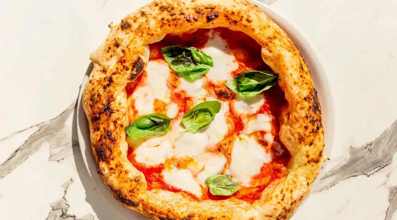 Eine köstliche Pizza Margherita mit geschmolzenem Mozzarella, Tomatensauce und frischem Basilikum. Perfekt für ein einfaches Pizza Margherita Rezept.