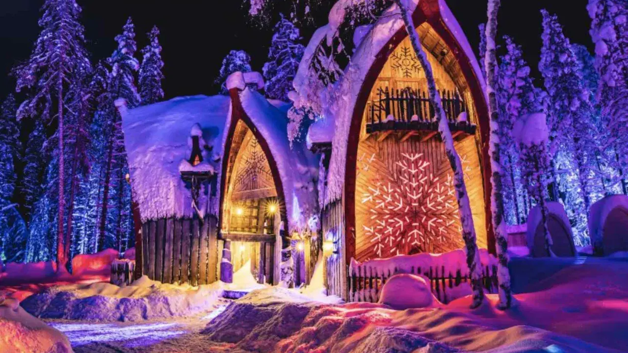 Noche mágica en Finlandia con niños. Casas nevadas iluminadas con luces de colores, rodeadas de árboles cubiertos de nieve.