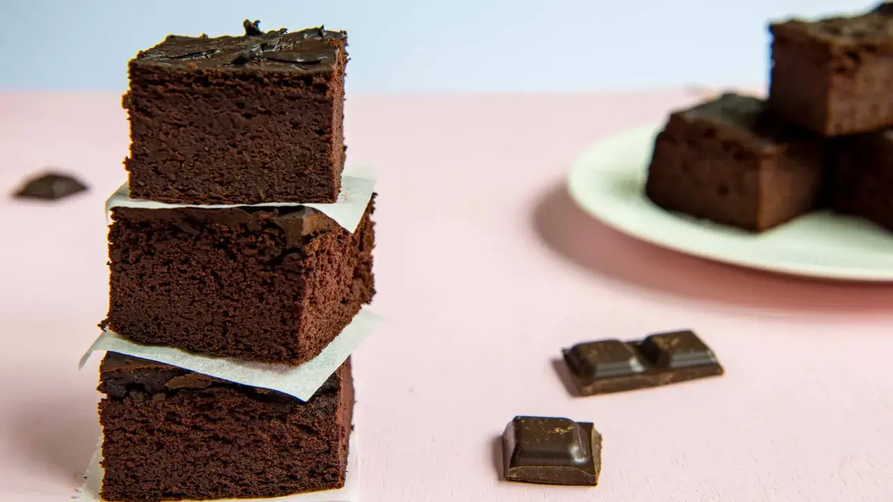 Ciemne, wilgotne brownie z fasoli, ułożone w wieżę, obok kawałków czekolady.