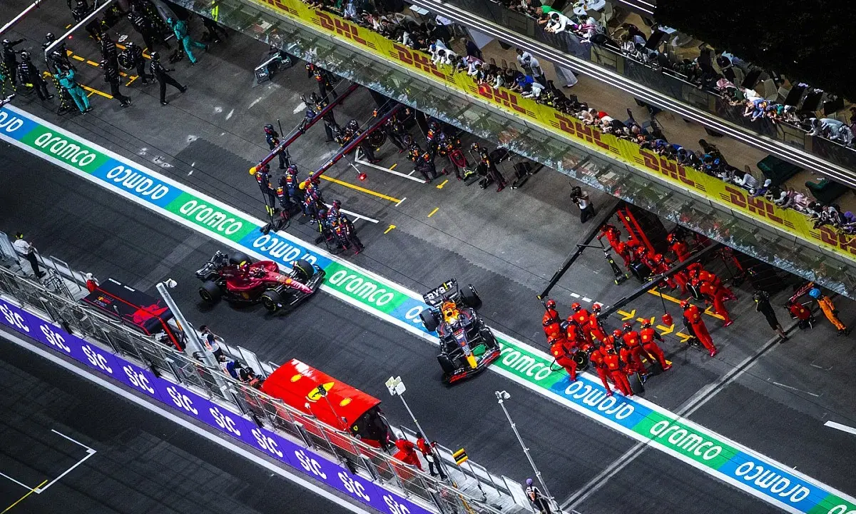 Equipos de F1 en boxes. Un coche Red Bull con un undercut f1 se detiene, mientras mecánicos de Ferrari se preparan.