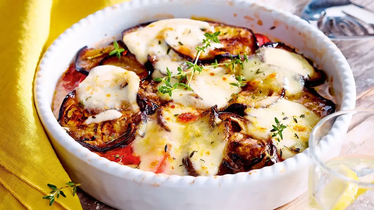 Ein köstlicher Auberginen Tomaten Auflauf mit geschmolzenem Käse und frischen Kräutern, bereit zum Genießen.