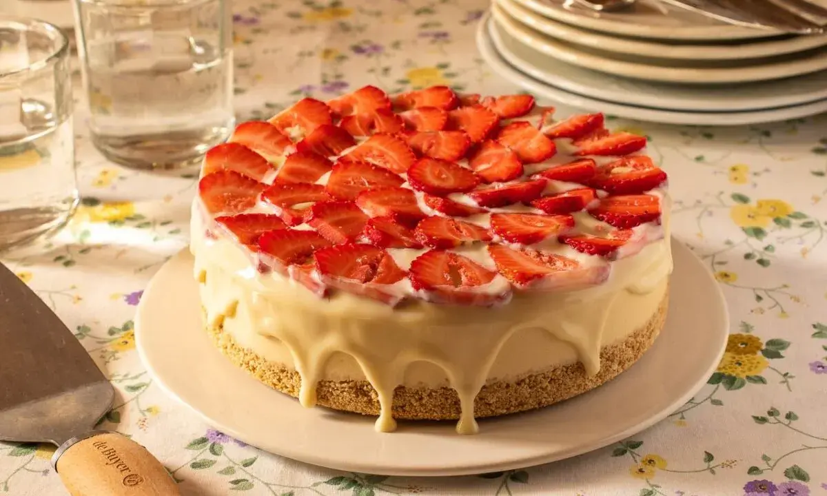 Deliciosa tarta de frutas cubierta de fresas frescas y glaseado blanco cremoso.