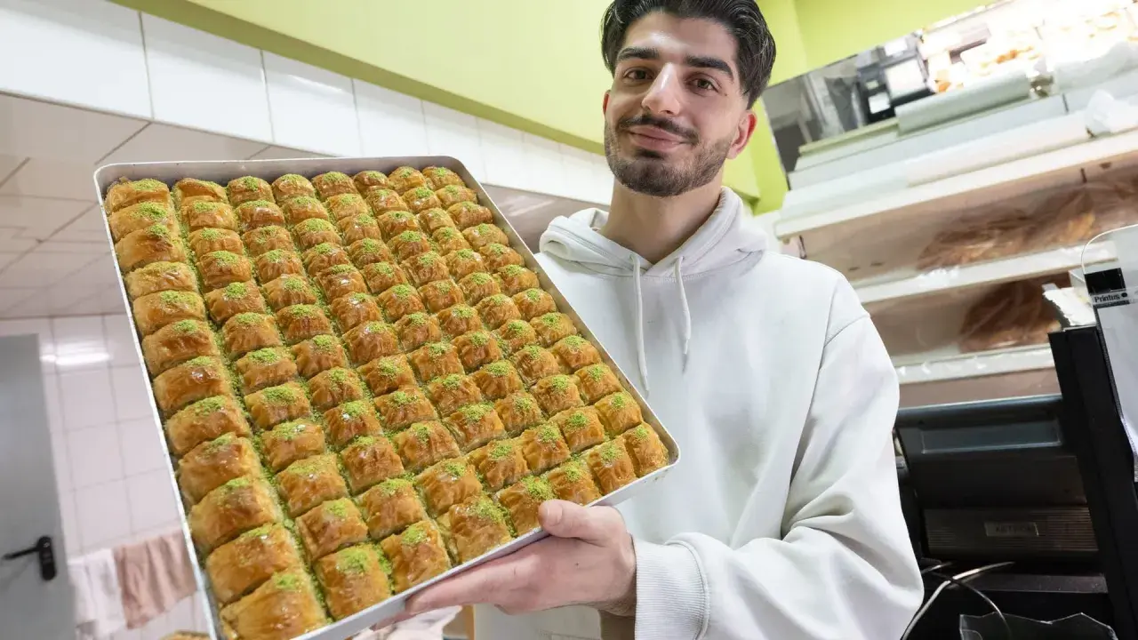 Mann hält eine große Blechschale mit Baklava, bereit für das Zuckerfest.