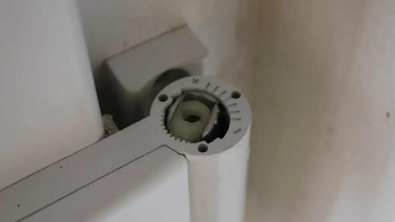 Mécanisme de réglage gond porte, avec une molette crantée et un axe carré pour ajuster la position.