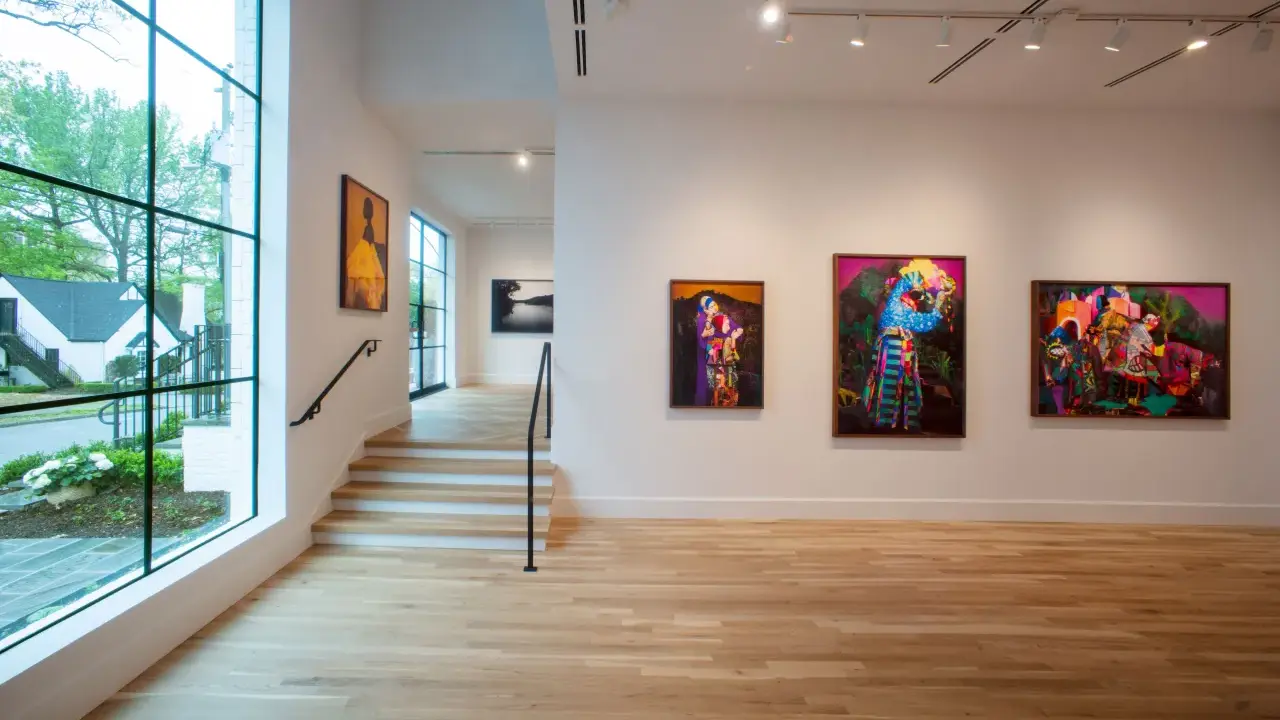 Vibrant artworks adorn the walls of Jackson Fine Art Atlanta, with a large window offering a glimpse of the lush greenery outside.