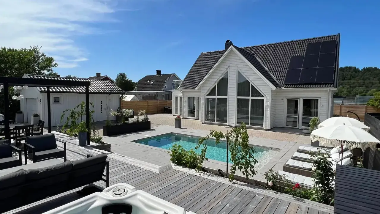 En lyxig pool altan med bubbelpool, solstolar och modernt hus. Perfekt pool altan inspiration för sommaren.