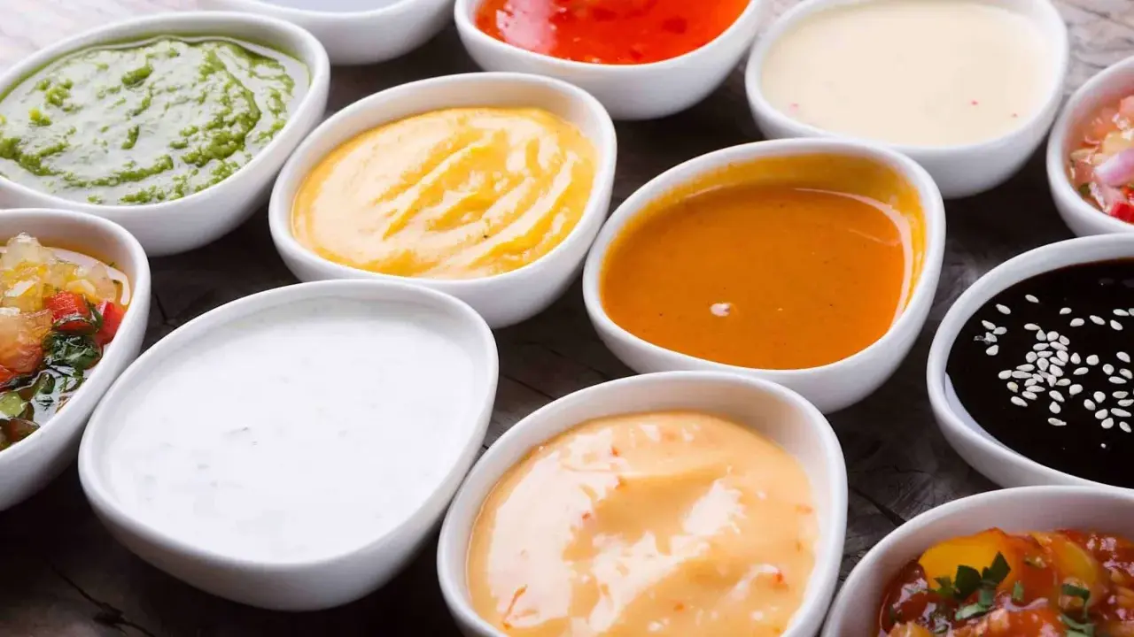 Assortiment de sauces pour raclette : verte, jaune, orange, blanche, rouge, noire. Un délice pour accompagner votre fromage fondu.