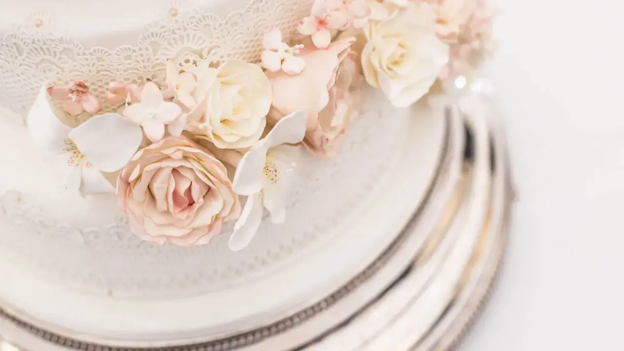 Elegancki tort na 150 osób, ozdobiony delikatnymi koronkami i pastelowymi kwiatami z masy cukrowej. Idealny na wielkie przyjęcie.