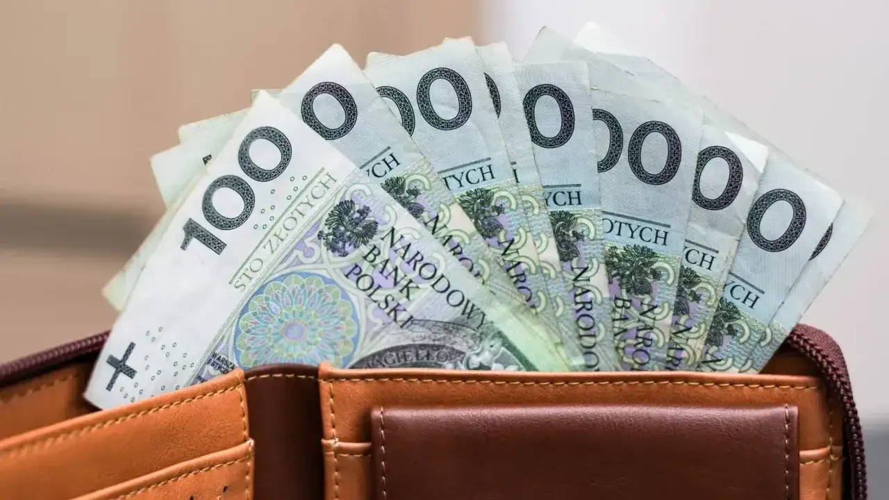 Pieniądze z wesela na konto: stos banknotów po 100 zł w brązowym portfelu.