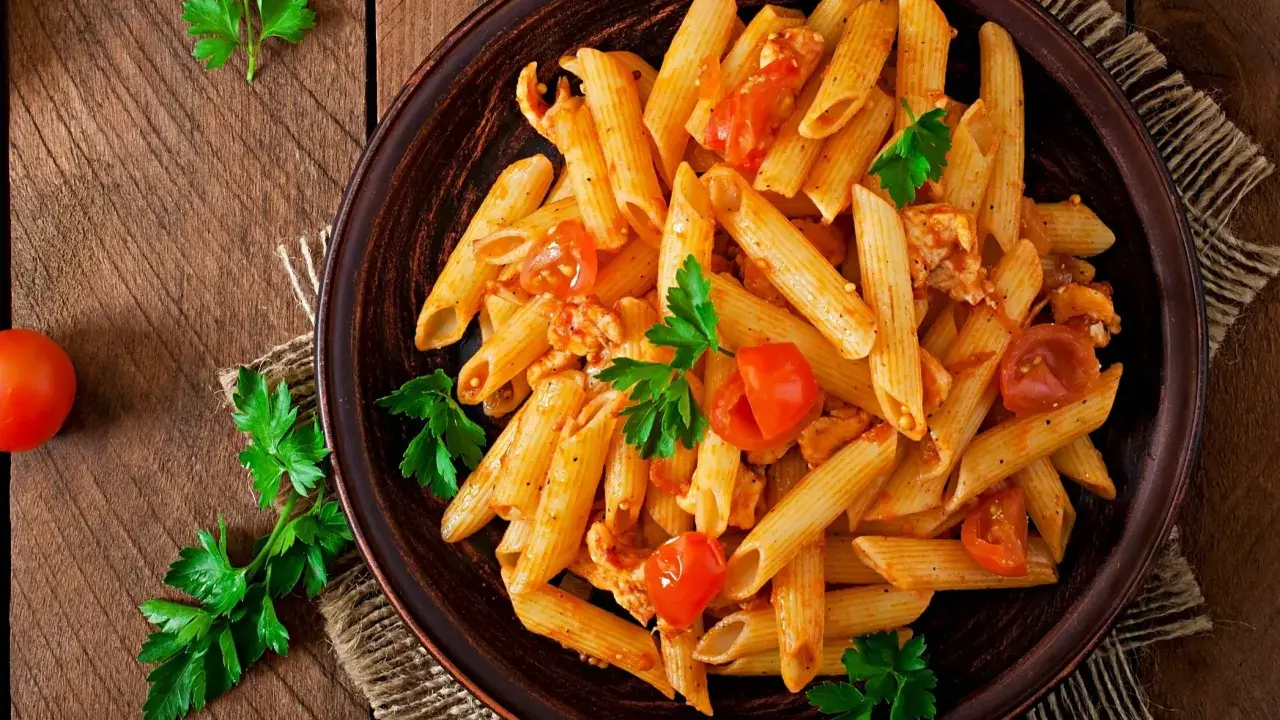 Penne z kurczakiem i pomidorami, udekorowane natką pietruszki. Idealne pytanie: co dzisiaj ugotować na obiad?
