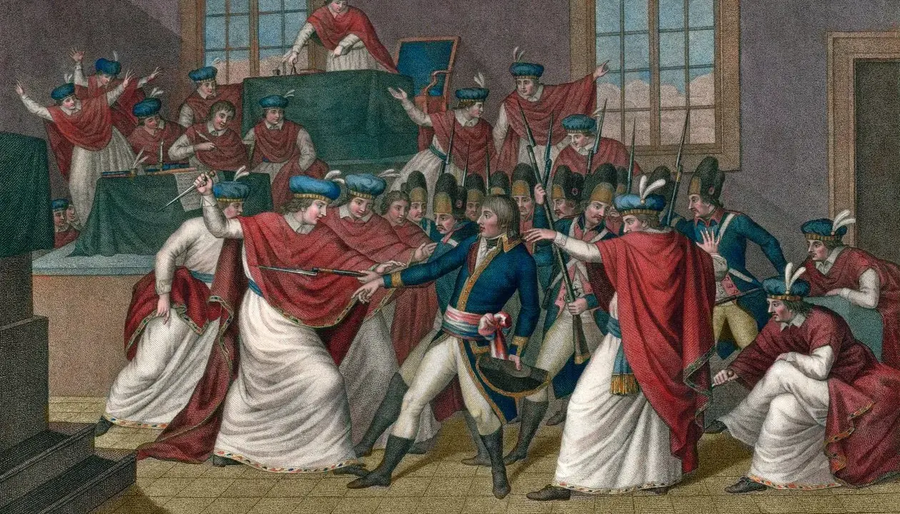 Napoleon Bonaparte im Zentrum, umgeben von Soldaten und Männern in roten Umhängen. Eine Szene des Staatsstreichs, die Machtübernahme wird dargestellt.