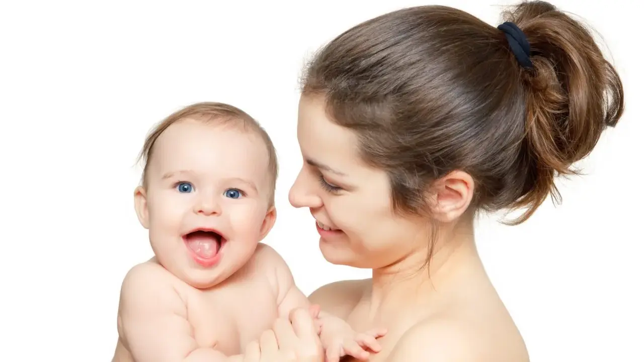 Uśmiechnięta mama tuli radosne dziecko. Pomimo nerwowa atmosfera w domu, dziecko rozjaśnia wszystko swoim uśmiechem.
