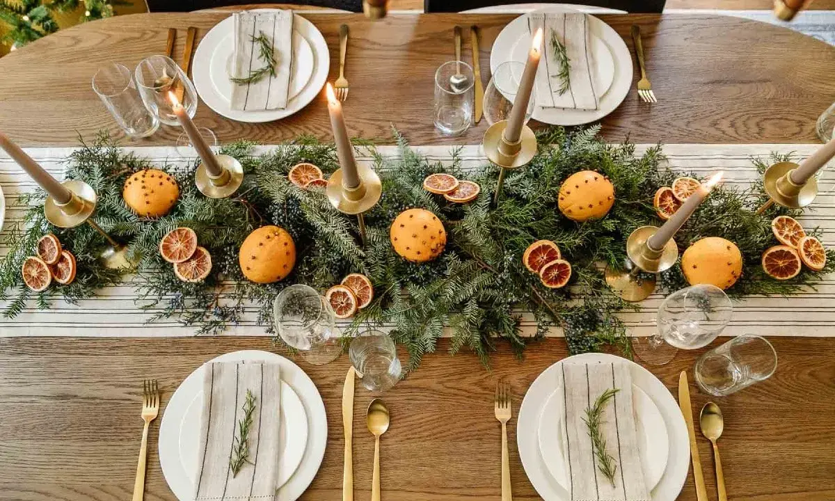 Vackert dukat julbord med granris, apelsiner med nejlikor, torkade apelsinskivor och ljus. En perfekt inspiration för att dekorera julbordet.