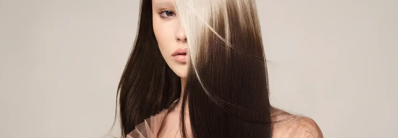 Mujer con cabello oscuro y mechones rubios claros, un estilo de **reverse balayage** que resalta su rostro.