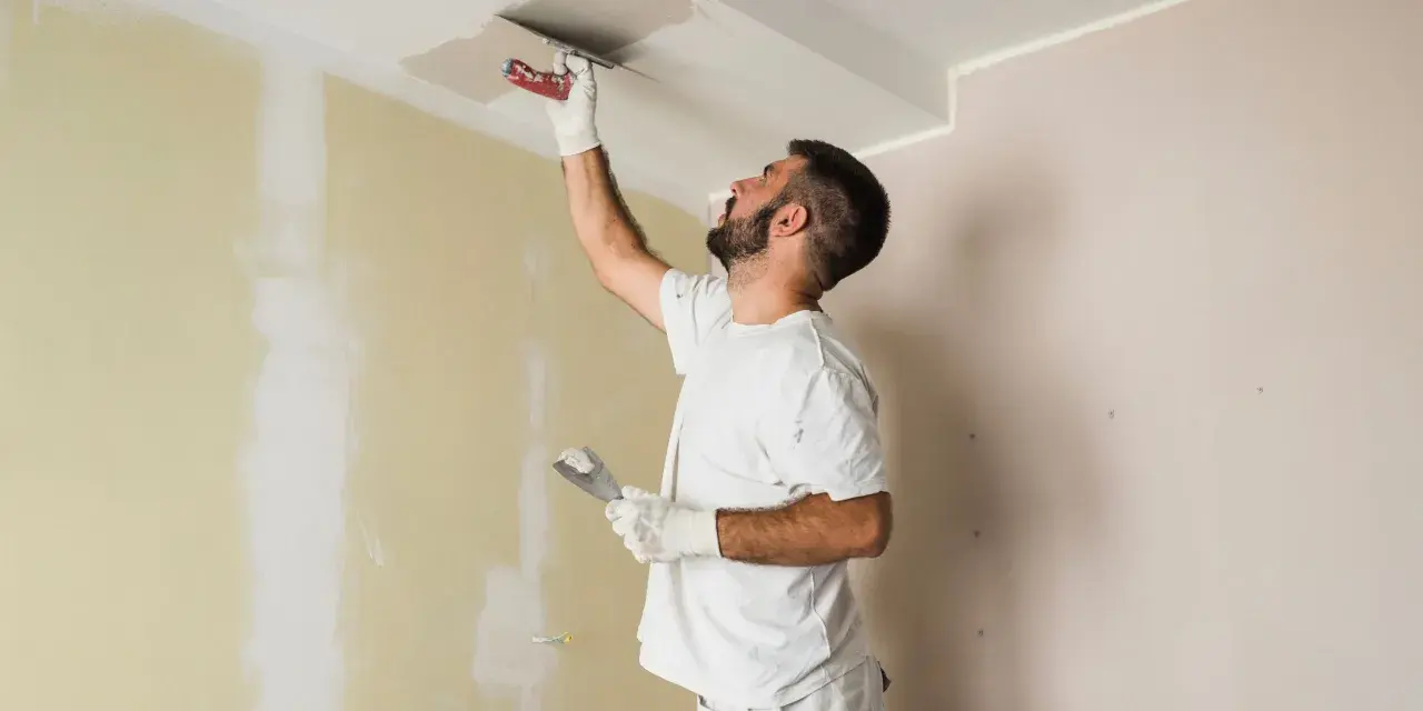 Hombre aplica mortero sobre techo pintado. Se puede aplicar mortero sobre pintura para reparaciones.