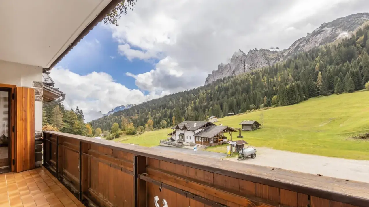 Vista da un balcone su una casa di montagna con prati verdi e boschi. Perfetta per una vacanza in montagna estate.