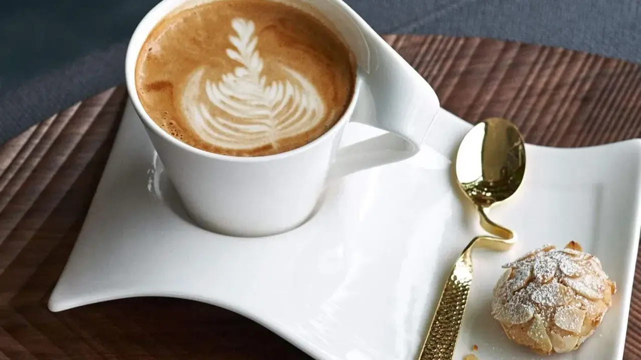 Ein Latte Macchiato mit schönem Milchschaum-Muster und ein Mandelgebäck, perfekt zum wiener Zubereiten.