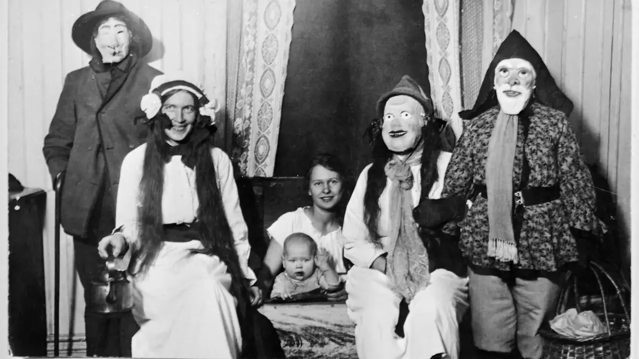 En familj klädd i masker och dräkter, kanske en del av julens historia, poserar för ett fotografi. En bebis sitter i förgrunden.