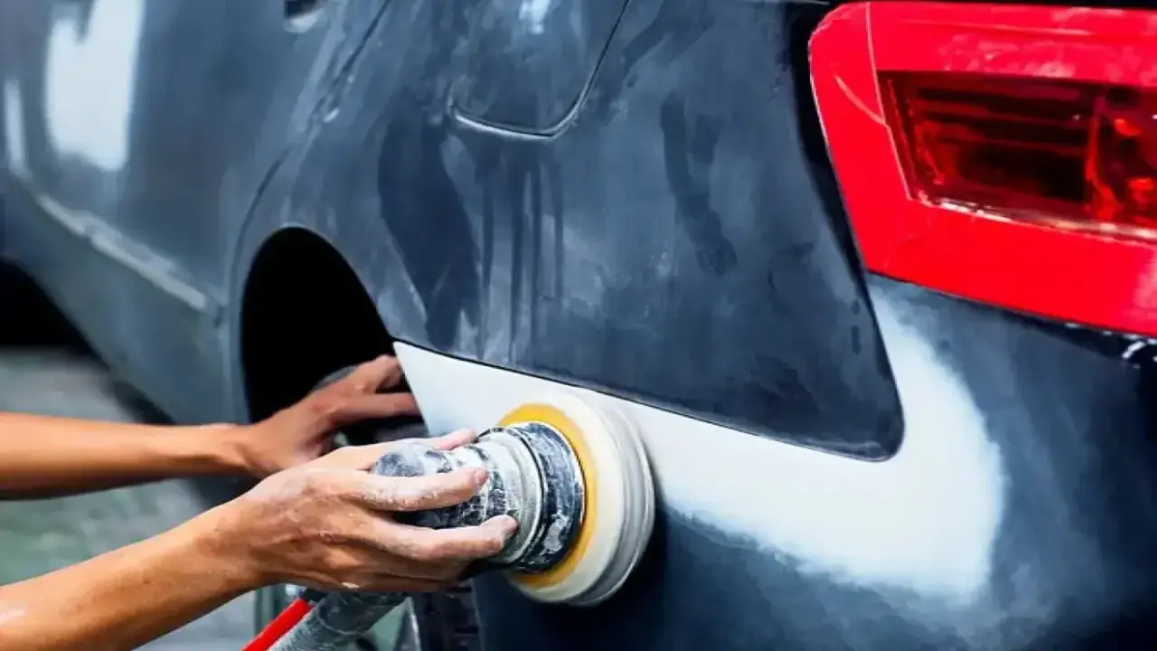 Mechanik szlifuje błotnik samochodu. Pytanie, czy benzyna ekstrakcyjna niszczy lakier, jest ważne przy takich pracach.