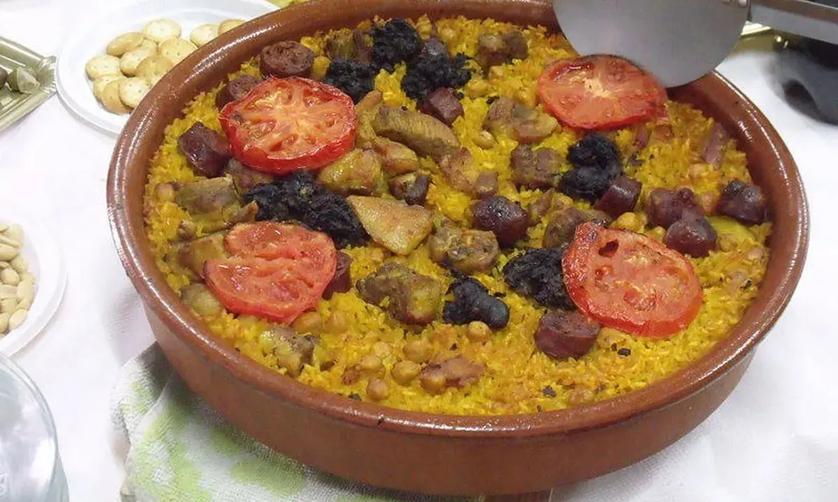 Un delicioso arroz al horno en cazuela de barro, con trozos de carne, chorizo, garbanzos y rodajas de tomate.