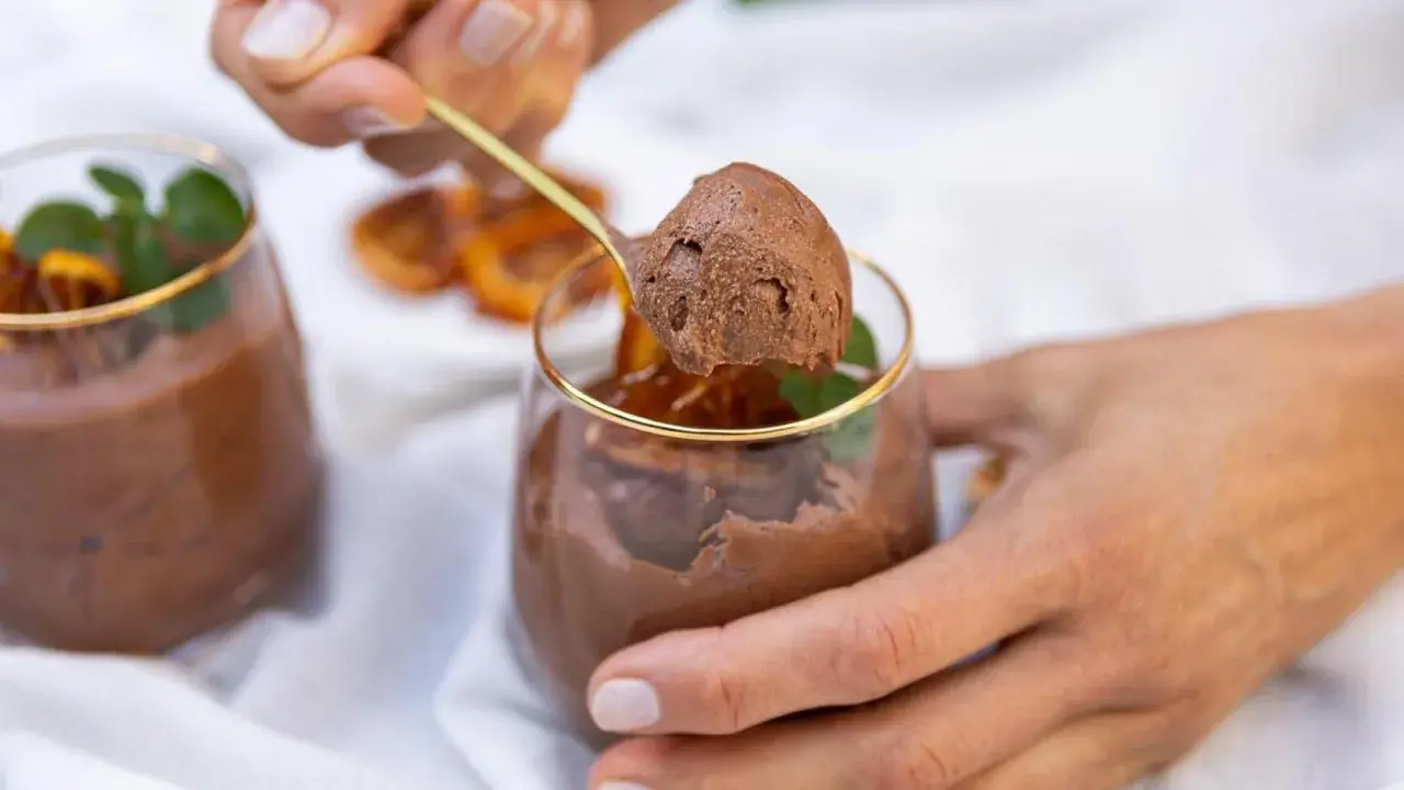 Delicioso mousse de chocolate, perfecto para los postres de Nochevieja. Una cucharada dorada revela su textura aireada.