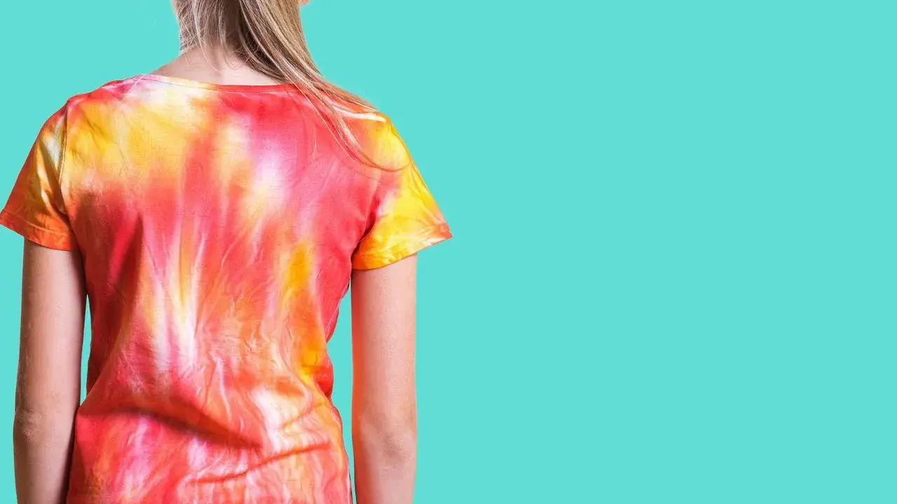 Dziewczynka w koszulce tie dye w odcieniach czerwieni i żółci.