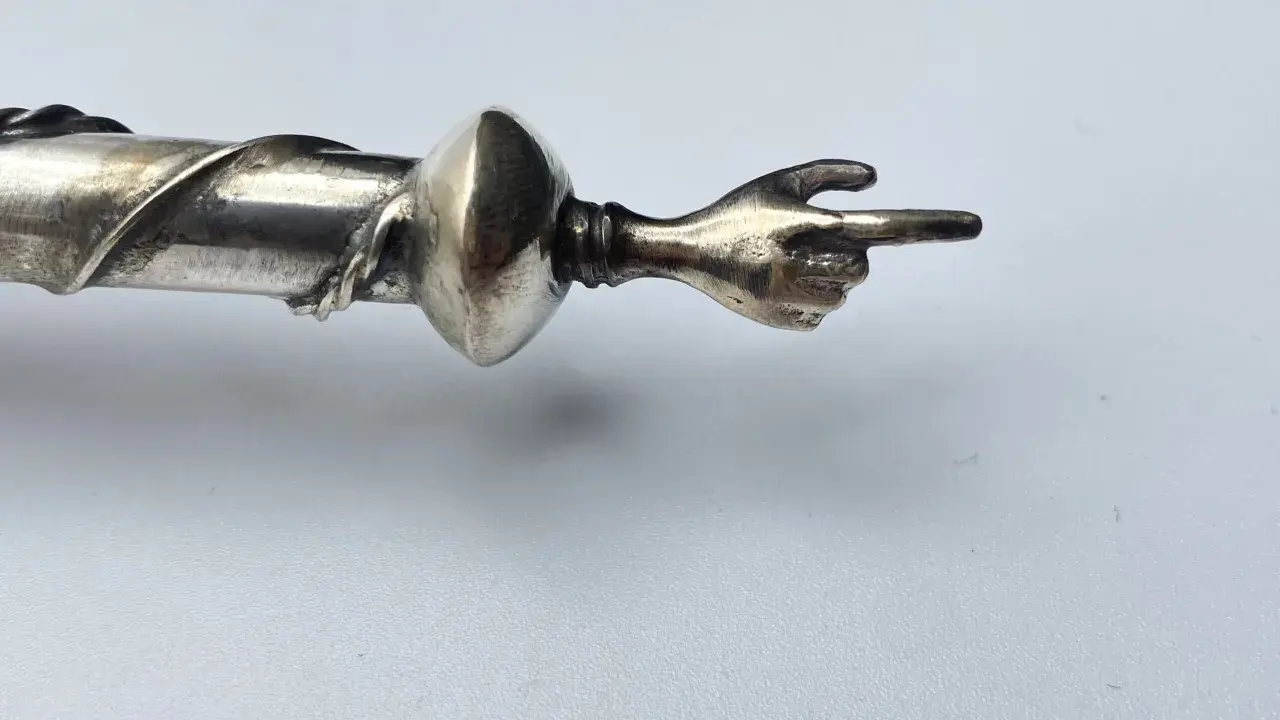 Manico in argento 325, cosa significa? Un dettaglio di un oggetto con una mano che indica.