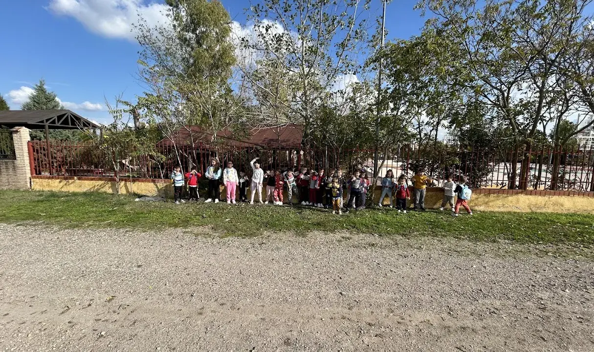 Niños y niñas posan en la granja escuela La Chopera, disfrutando de un día soleado rodeados de árboles y vegetación.