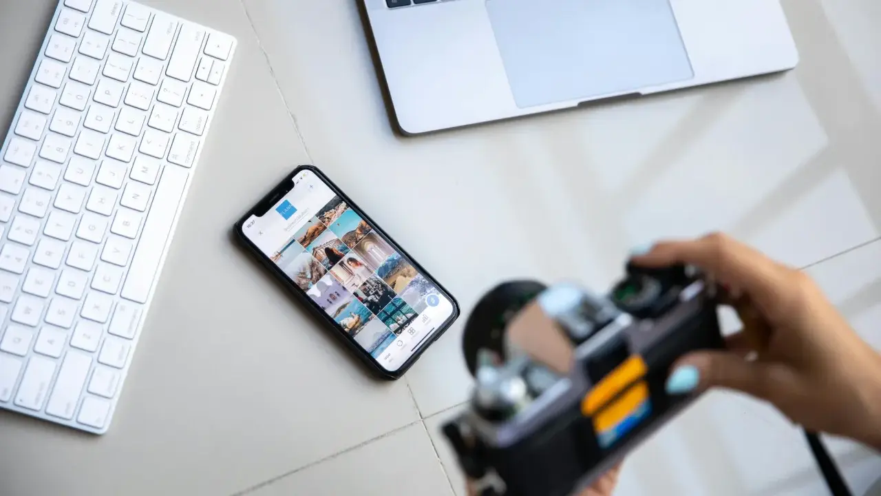 Aparat fotograficzny służy do uwieczniania chwil. Obok klawiatury, telefonu z Instagramem i laptopa, jest gotowy do pracy.