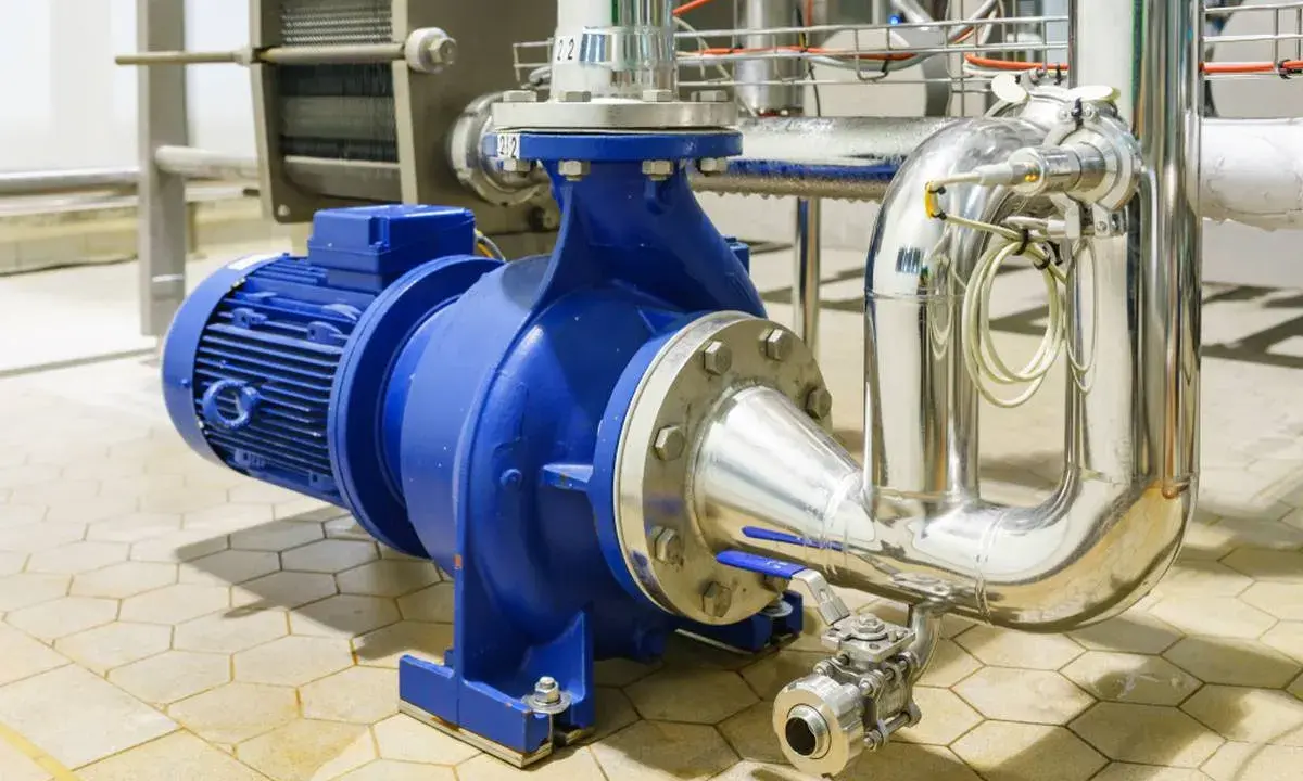 Pompe à eau industrielle bleue, connectée à des tuyaux en acier inoxydable. Un système essentiel pour gérer la pression eau maison.