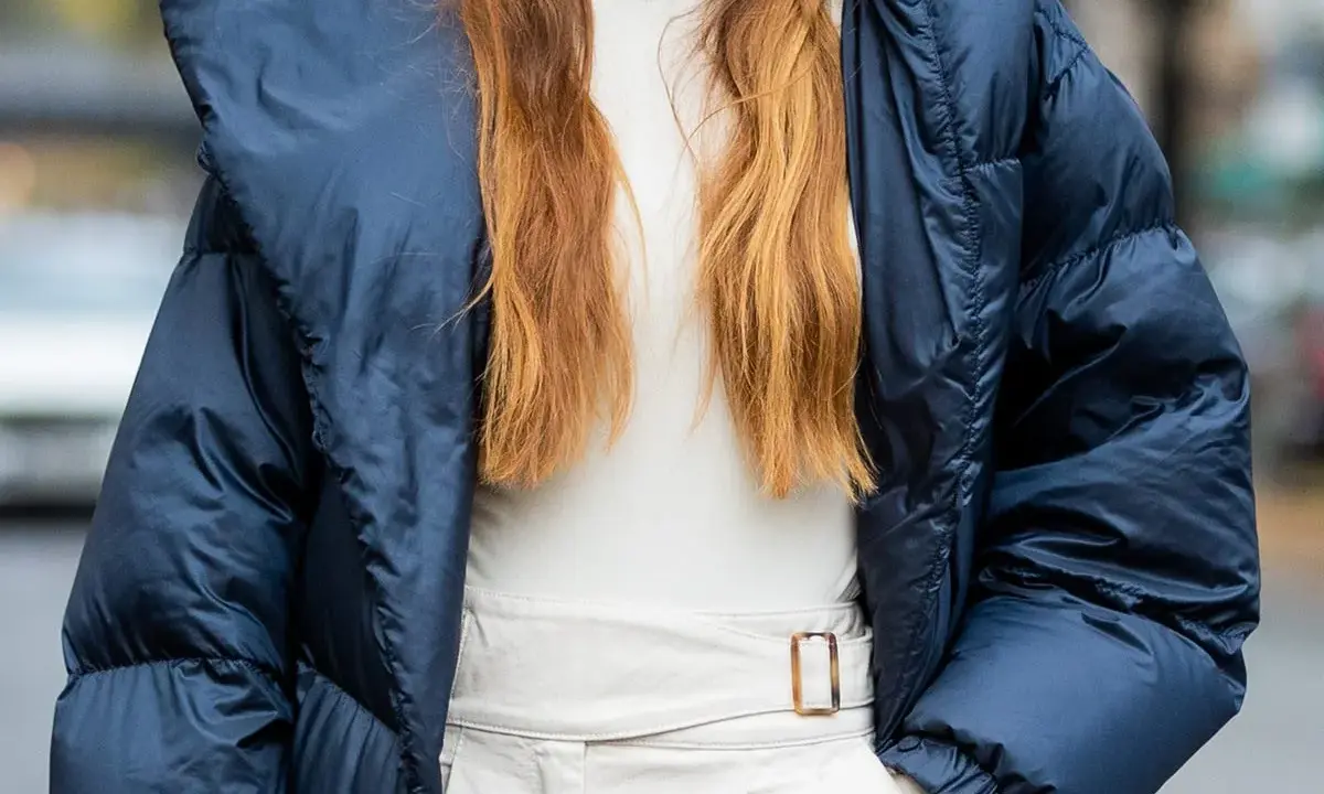 Outfit maestra asilo: piumino blu, dolcevita beige e pantaloni chiari con cintura.