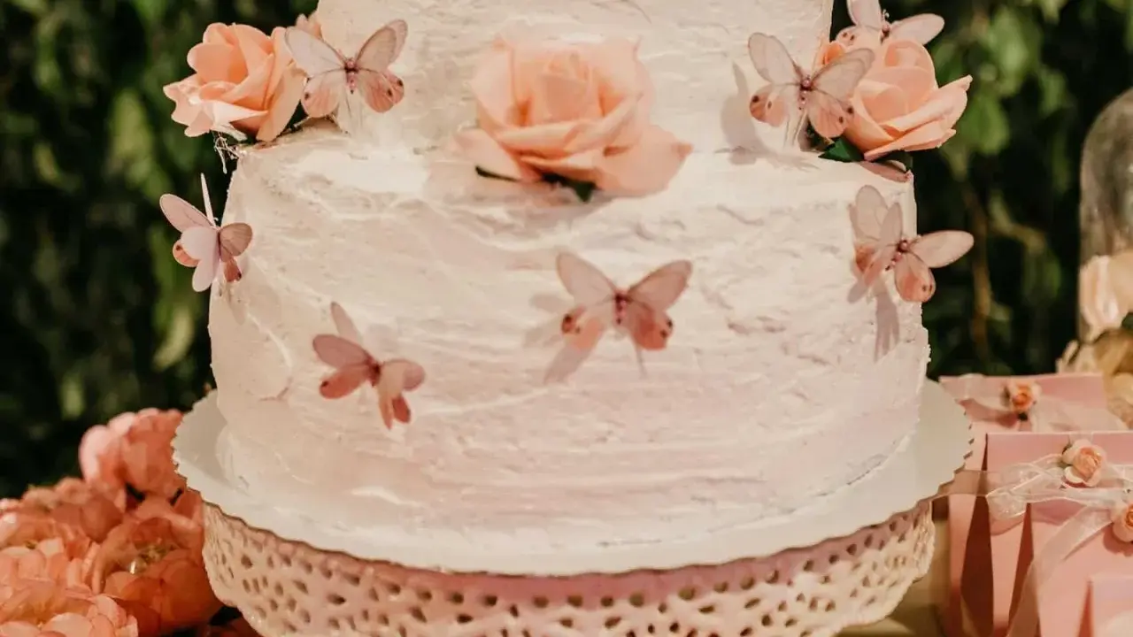 Gâteau à étages décoré de roses et de papillons, recouvert d'une délicate crème au beurre.