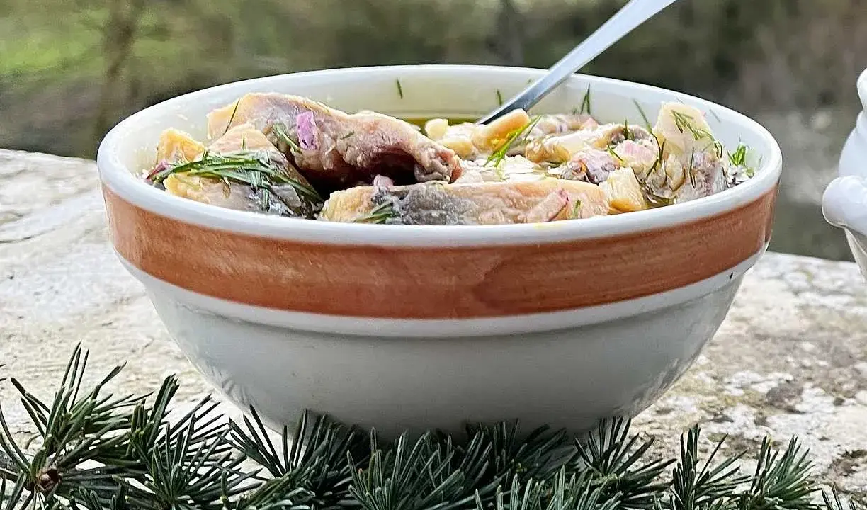 En skål med inlagd sill, dill och blommor. Perfekt för ett svenskt midsommarfirande eller som en del av ett inlagd sill recept.