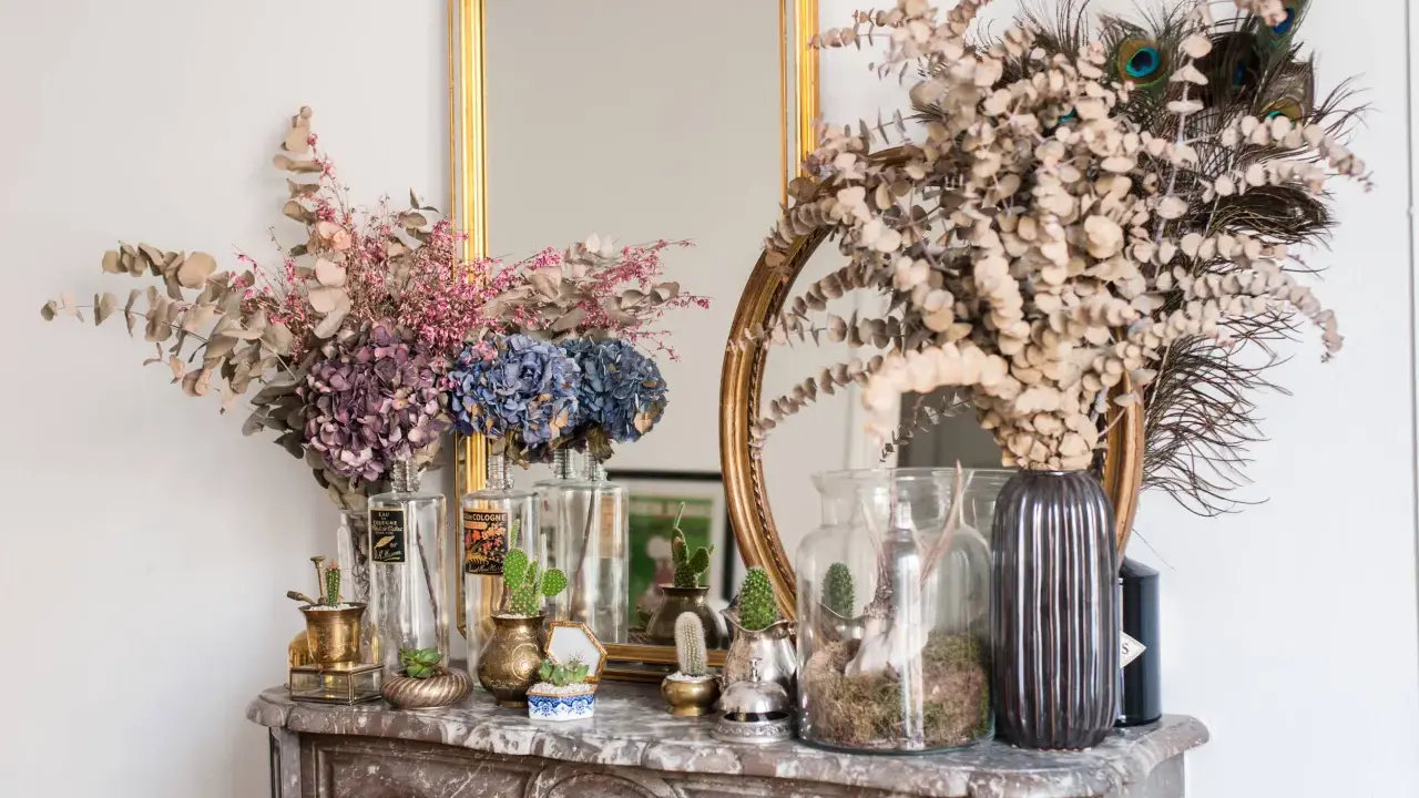 Des idées pour que faire avec des hortensias séchés : bouquets, décorations avec des plumes de paon et des cactus sur une cheminée en marbre.