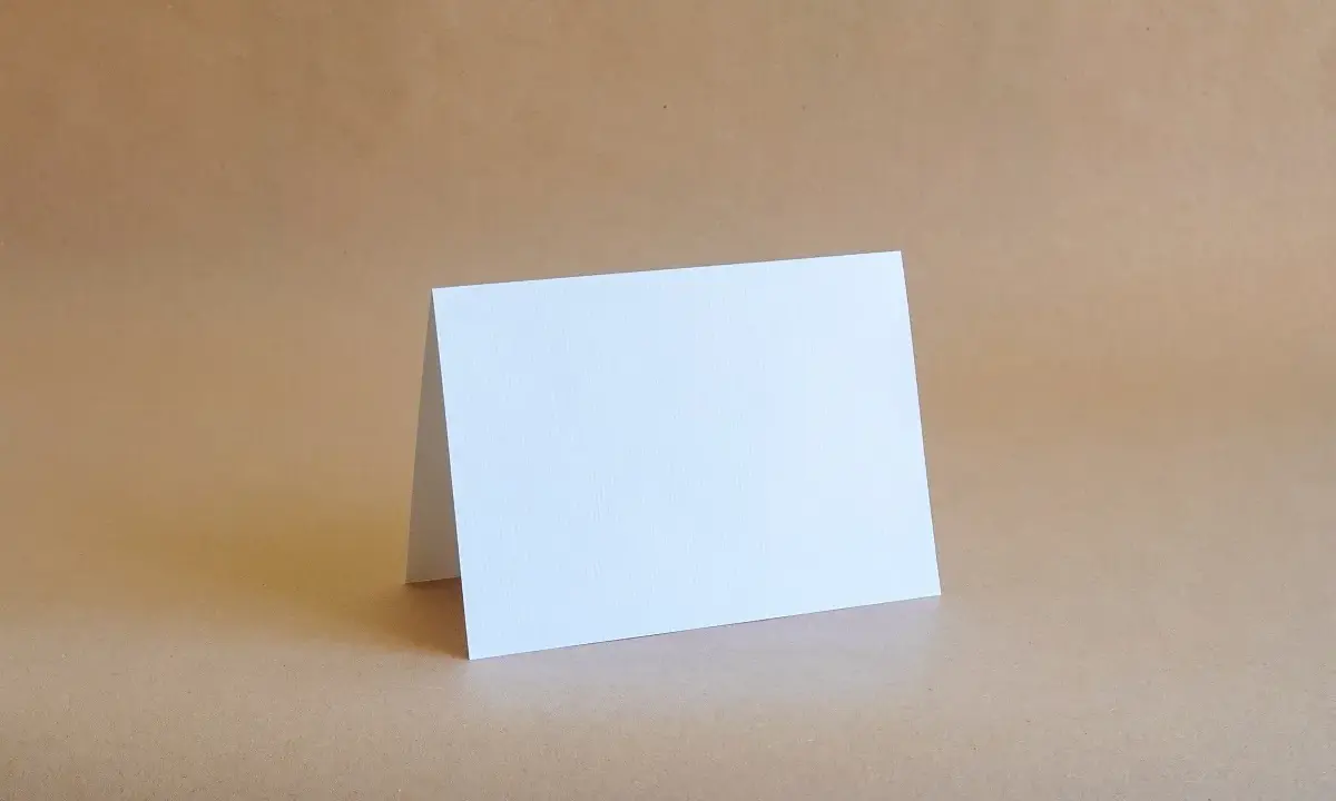 Biała kartka formatu B6 (12,5 x 17,6 cm) złożona na pół, gotowa na Twoje życzenia.