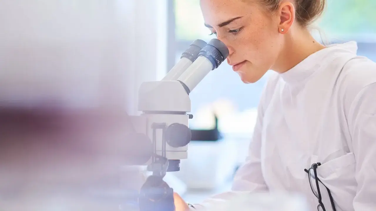 Ricerca scientifica per capire cos'è il sarcoma. Giovane scienziata al microscopio.