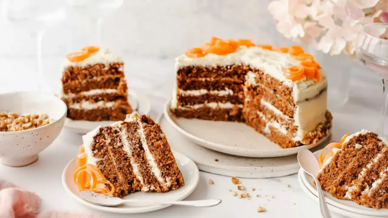 Delicioso pastel de zanahoria con glaseado cremoso y decoraciones de zanahoria. Varias porciones listas para disfrutar.