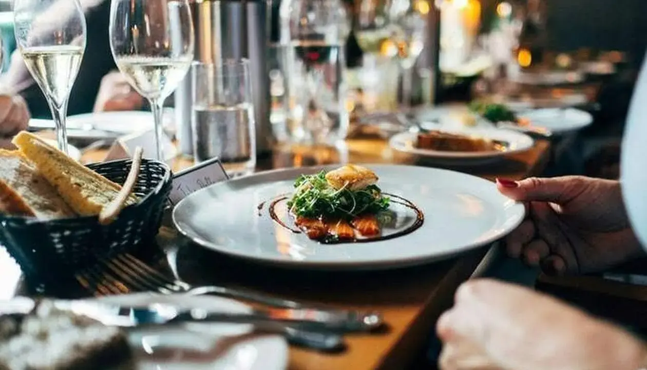 Une assiette de saumon avec garniture verte, du pain dans un panier, des verres de vin et des bougies allumées. Bon appétit !