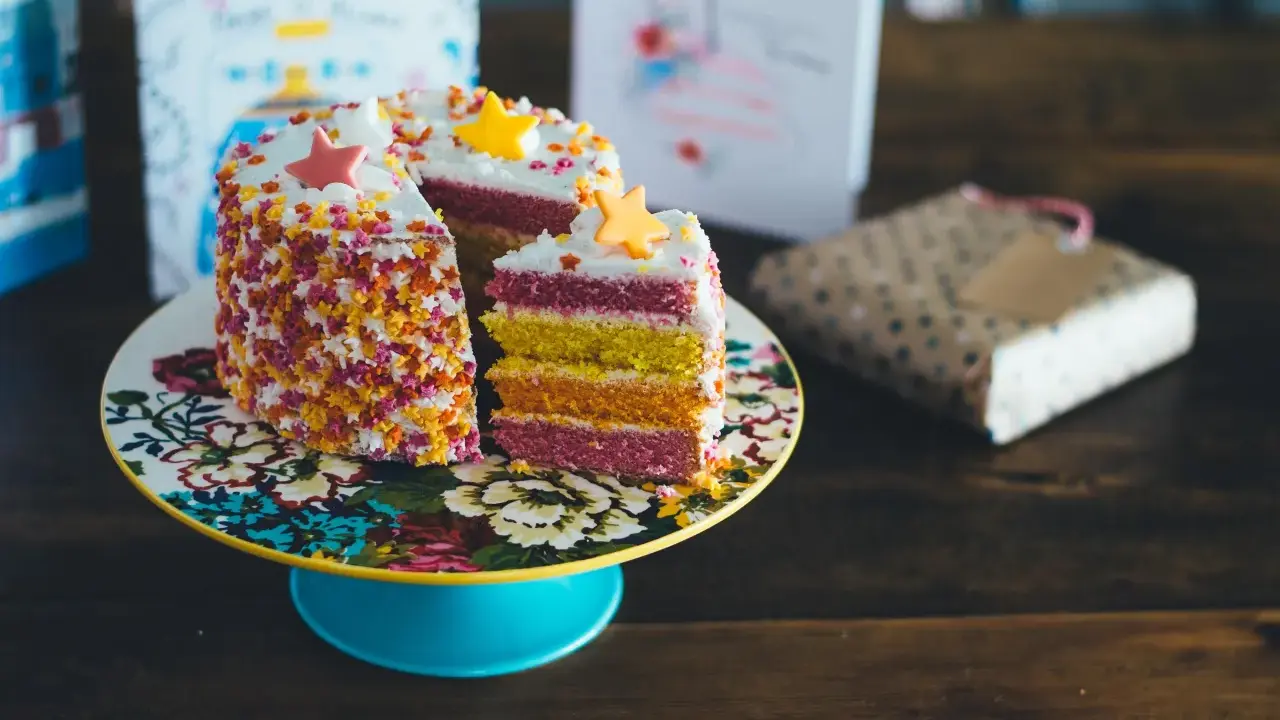 Pastel de capas arcoíris con estrellas de azúcar y chispas. ¡Ideas para decorar tartas que inspiran alegría y color!