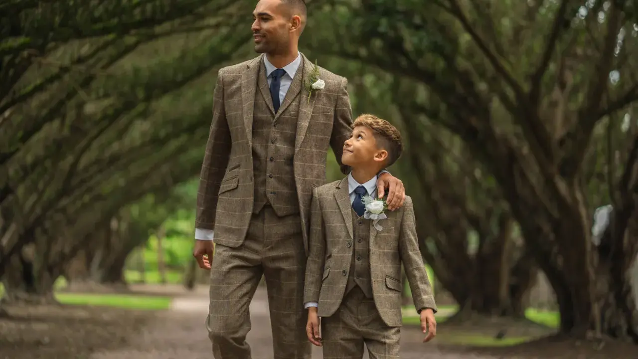 A man and boy in matching tweed suits, a perfect example of what formal attire means for a wedding.