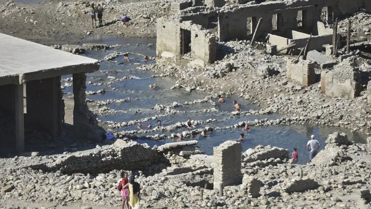 Ruinas de las termas de Yesa, con gente bañándose en las piscinas naturales formadas entre los escombros.
