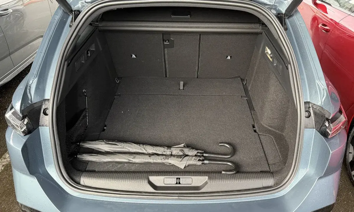 Maletero abierto de un Peugeot 308 SW con dos paraguas negros. Las medidas del maletero son amplias para equipaje.