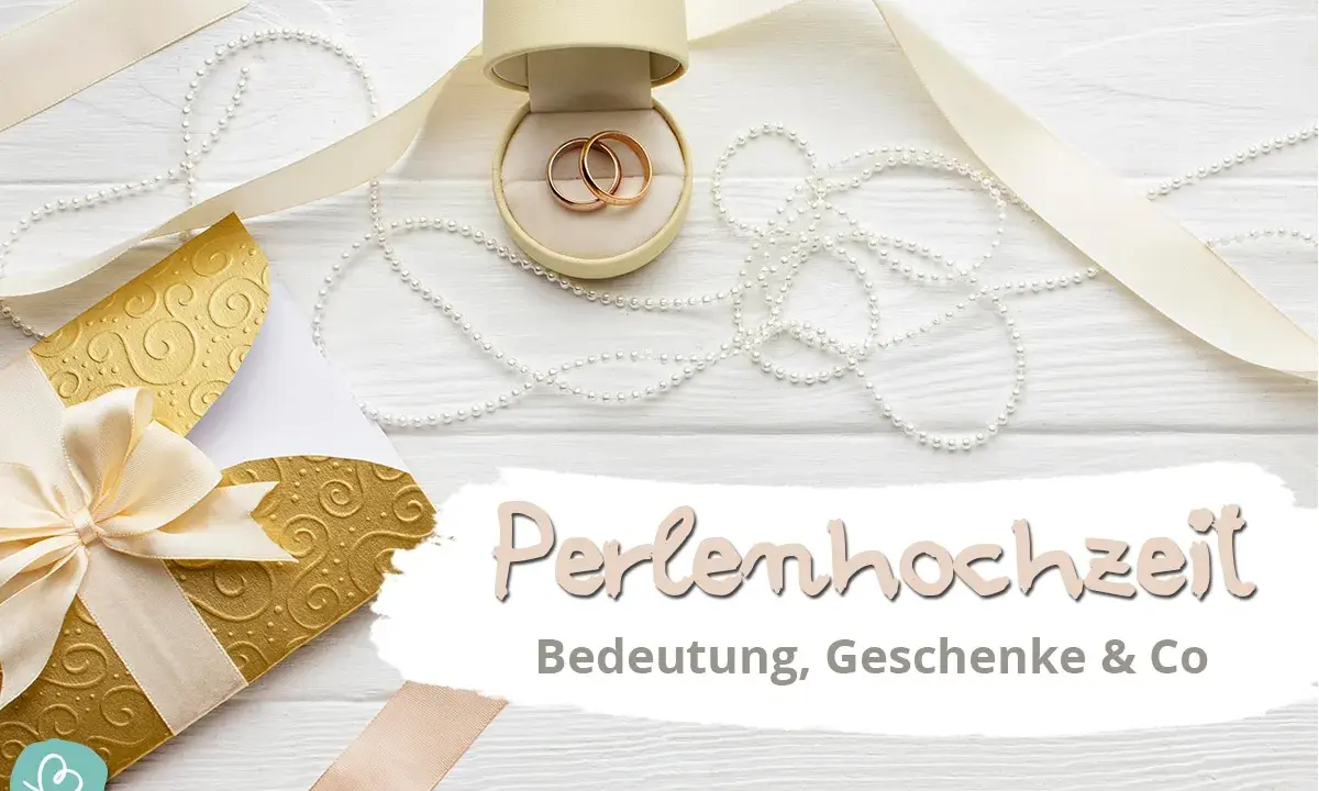 Hochzeitstags-Deko mit Ringen, Perlen und goldenem Umschlag. Die Perlenhochzeit Bedeutung wird hier gefeiert.
